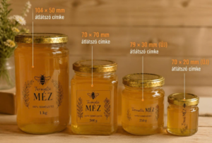 Átlátszó címkékkel ellátott különböző méretű mézesüvegek.